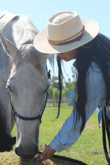 Luisana alimentando caballo blanco